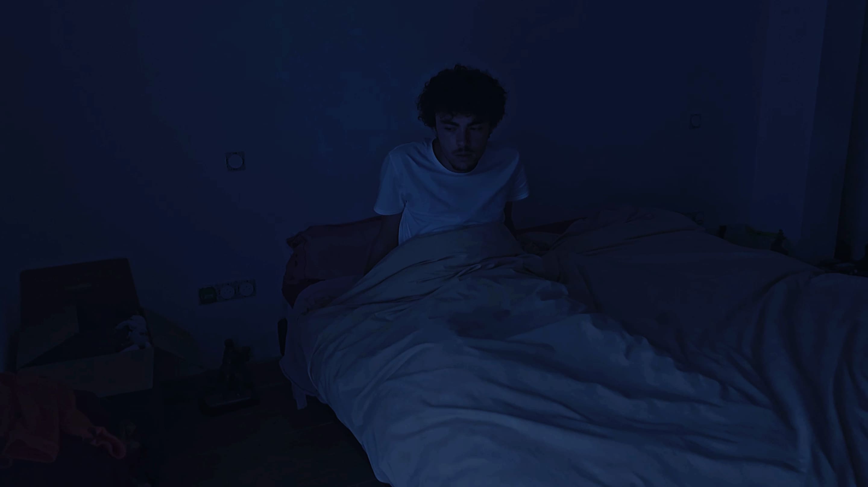 3e photographie de Shattered Reality où un homme s'est réveillé au milieu de la nuit. Le plan est large et a une teinte bleu marine.